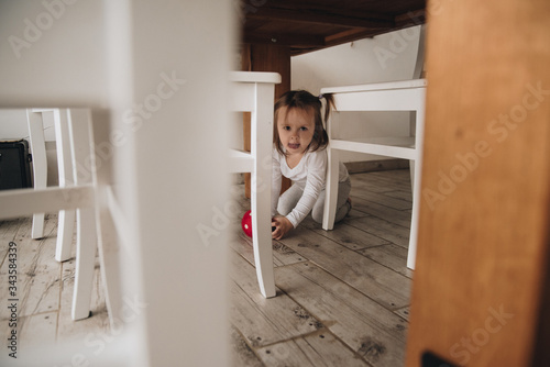 Family in a big house. Lifestyle Home comfort. Children at home. Textile. Brown sofa, yellow pillows. Portrait of a child. Two-storey house. The girl in gray clothes. Two tails. Under the table.