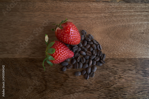 Coffee beans and strawberry on wood table
