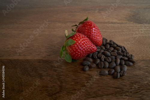 Coffee beans and strawberry on wood table