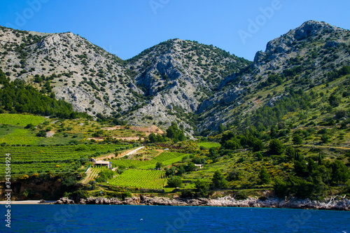 Cultivated slopes on the island of Brac in Croatia in the Adriatic Sea - Green fields surrounded by rugged peaks seen from a boat
