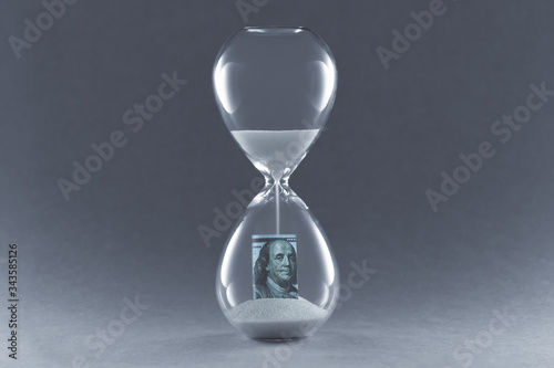 Hourglass on dark background. Concept passing traditional currency time. End of dollar currency.
