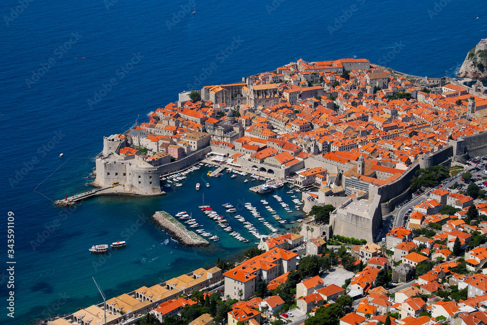 Aerial view of Dubronik's walled old medieval city on the coast of the Adriatic Sea in Croatia - Old port with excursion boats