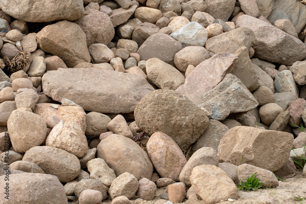 a pile or pile of rocks on the beach. A lot of big stones.