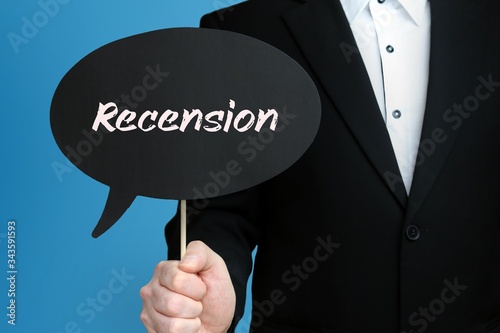 Recension. Businessman in suit holds speech bubble at camera. The term Recension is in the sign. Symbol for business, finance, statistics, analysis, economy photo