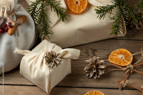 Zero waste christmas concept. Packed in natural fabric gifts and decorations from natural materials on a wooden table