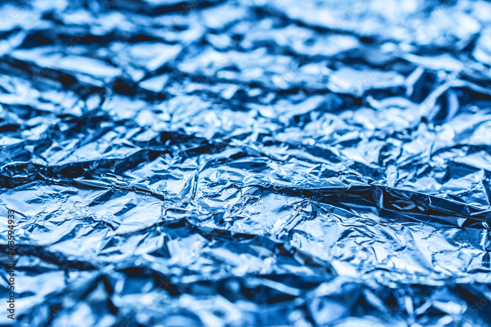 Fototapeta premium blue background of crumpled foil. shiny metal foil as a blue background or texture