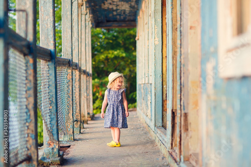 little girl standing on porch of old ruined house.
