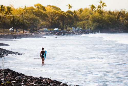 Photography lady standing on the shoreline ready to go surfing