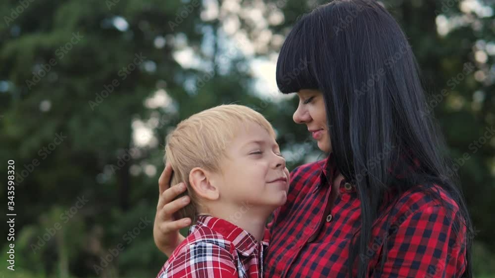 happy family mom and son concept . mom tender childhood video . slow motion video lifestyle . mom a brunette girl gently hugs takes care of the boy son blonde outdoors happy family mom and son concept . mom tender childhood video . slow motion video lifestyle . mom a brunette girl gently hugs takes care of the boy son blonde outdoors