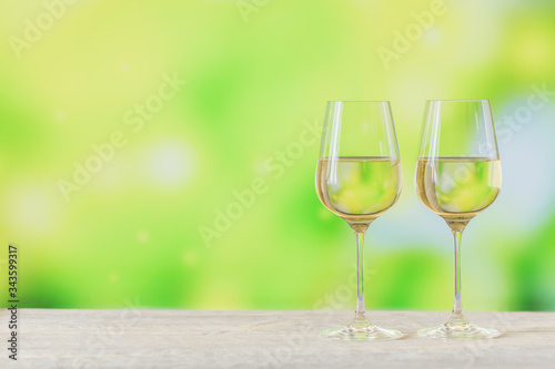 Two glasses of white wine on light green background. Wine mood concept