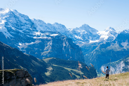 A man standing on a meadow facing the Junfrau mountain range in switzerland