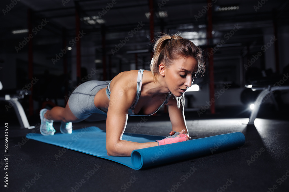 Young beautiful woman in sportswear doing plank exercise on the fitness mat in gym or yoga class. Health concept. Young beautiful woman in sportswear doing plank exercise on the fitness mat in gym or yoga class. Health concept.