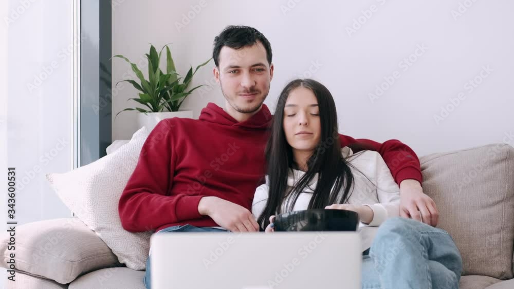 The boyfriend and girlfriend are at home watching films. The couple is eating popcorn and smiling. The boyfriend and girlfriend are at home watching films. The couple is eating popcorn and smiling.