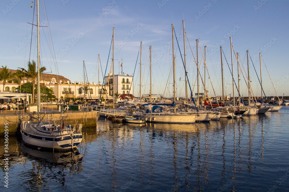 boats in a beautiful golden sunlit harbour in puerto de mogan, gran canaria spain