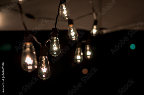 String of lightbulbs hanging from a tent at night © Michael Deemer