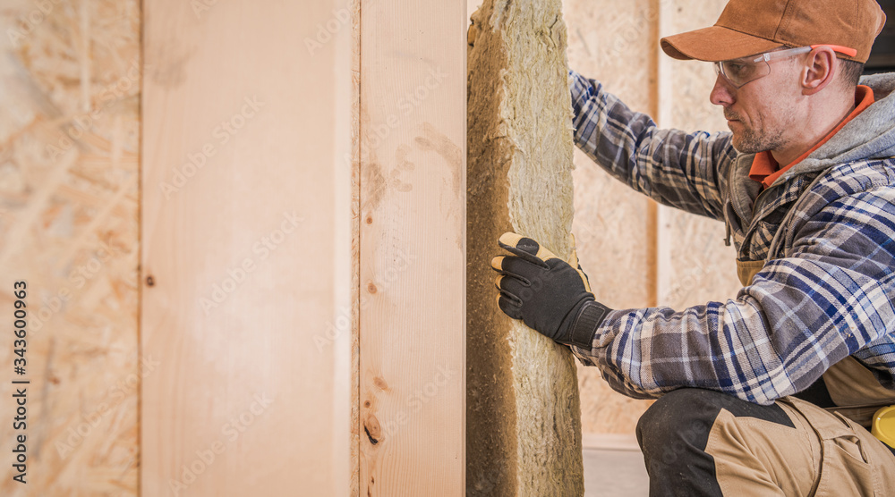 Worker Insulating House Walls with Piece of Mineral Wool Worker Insulating House Walls with Piece of Mineral Wool