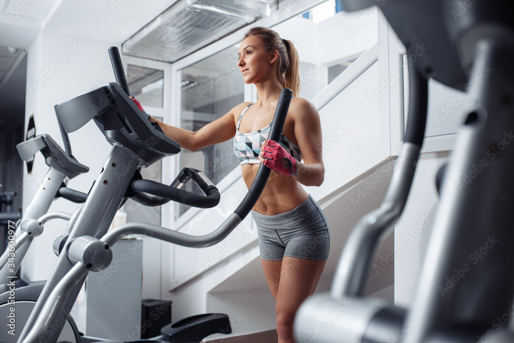 Fit young woman doing cardio on the xtrainer machine in gym. Fat burn. Health concept. Weight loss. Fit young woman doing cardio on the xtrainer machine in gym. Fat burn. Health concept. Weight loss.