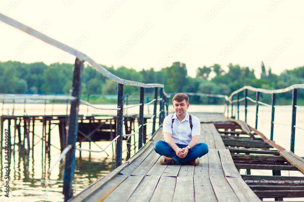 man in sitting old bridge on the background river. man in sitting old bridge on the background river.