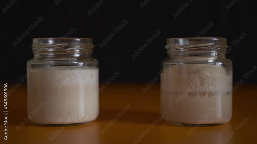 two jars of yeast are fermented in turn. To the left is ordinary yeast. Dry on the right. Black background. Time Lapse two jars of yeast are fermented in turn. To the left is ordinary yeast. Dry on the right. Black background. Time Lapse