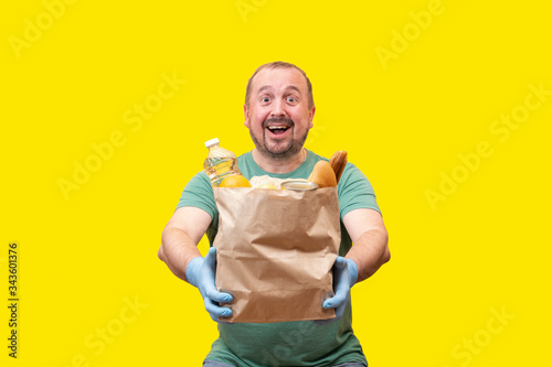The volunteer is a man his 40s in a green t-shirt and blue medical gloves.Smile broadly and holds a bag of vegetable oil and bread. donations of products for distribution during the Covid-19. isolated
