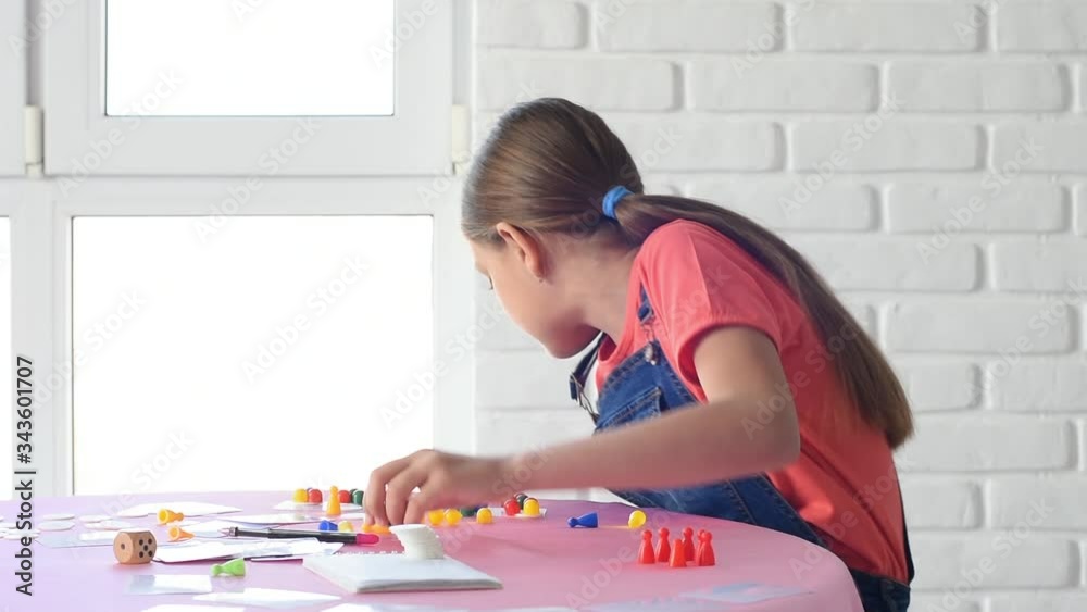 The girl alone plays board games at home and dropped the chip on the floor