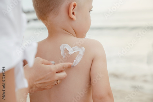 a protective cream on a baby. Mother lubricates her son with cream on vacation near the sea.