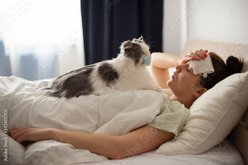 young girl lies in bed with a fever fluffy cat treats her. Coronovirus patient