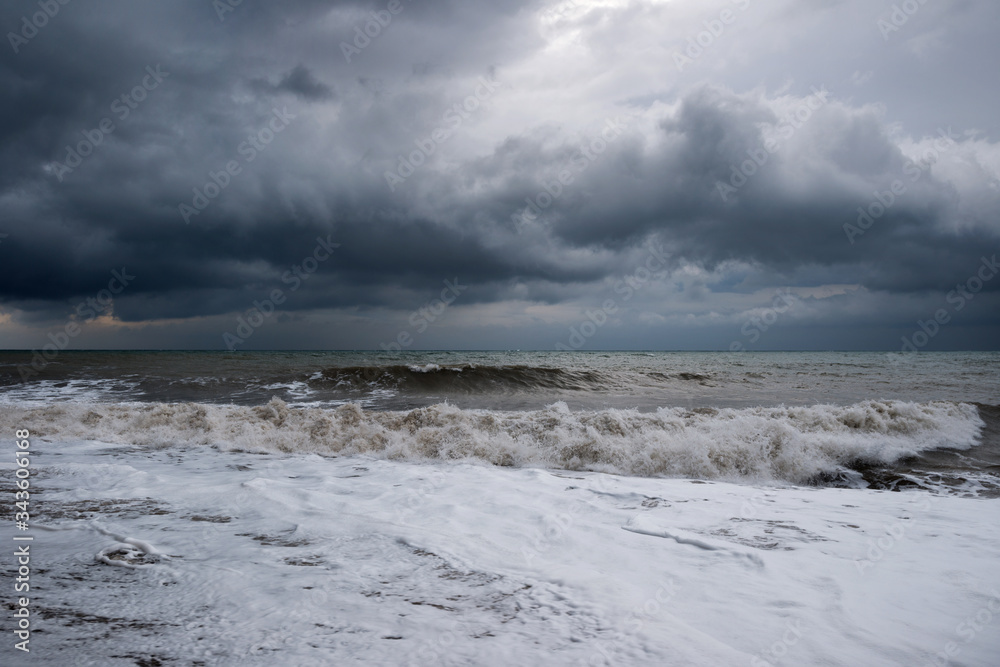 Winter storm on the Black sea in Crimea. Dirty water, white foam and dark clouds in the background.