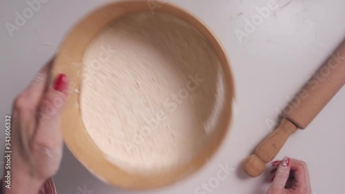 A woman sifts flour through a sieve, top view. Women's hands with a sieve sift flour. The POV view.