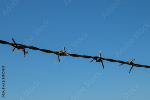 Tense barbed wire against a blue sky