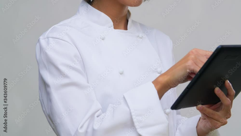 cooking, culinary and people concept - female chef in toque with tablet pc computer over grey background cooking, culinary and people concept - female chef in toque with tablet pc computer over grey background
