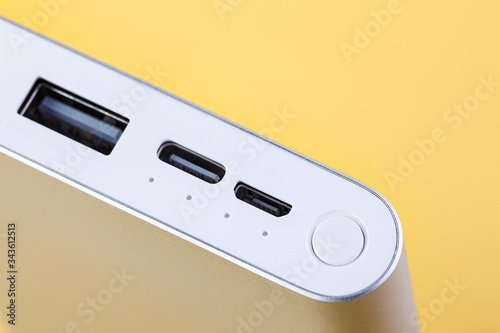 An additional stand-alone power bank for charging mobile devices. External battery on a yellow background. White charger for smartphone, power supply (battery bank). Selective focus.