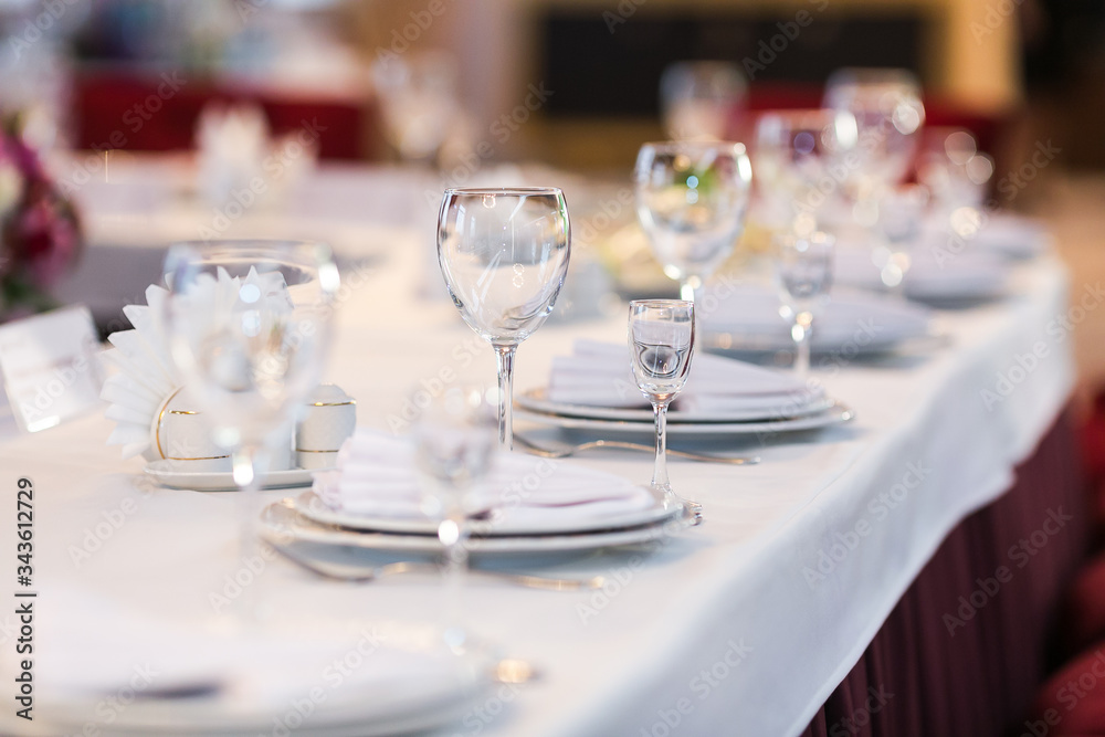 Table settings with white wine glasses and glasses of spirits. Wedding decor, restaurant layout.