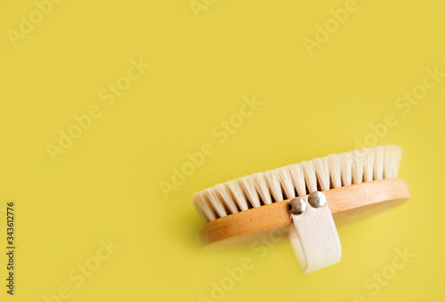 Anti-cellulite brush for dry body massage. Lymphatic drainage body massage. On yellow background copy space