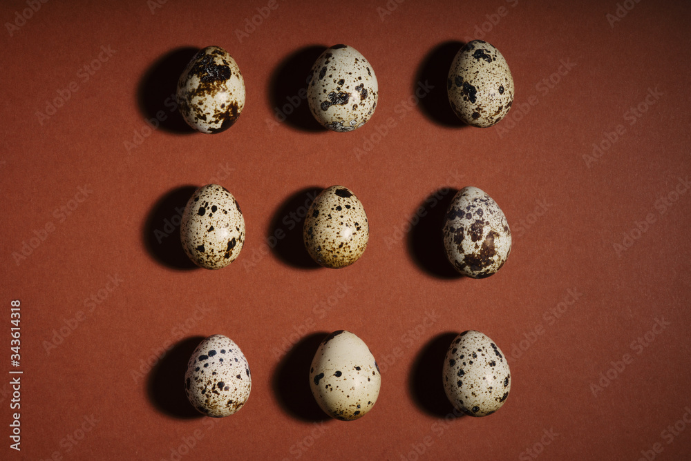 Creative quail egg layout on brown background. Quail eggs pattern. Happy easter concept. Creative food layout. Healthy breakfast, diet food concept. Colorful easter eggs. Copy space, flat lay
