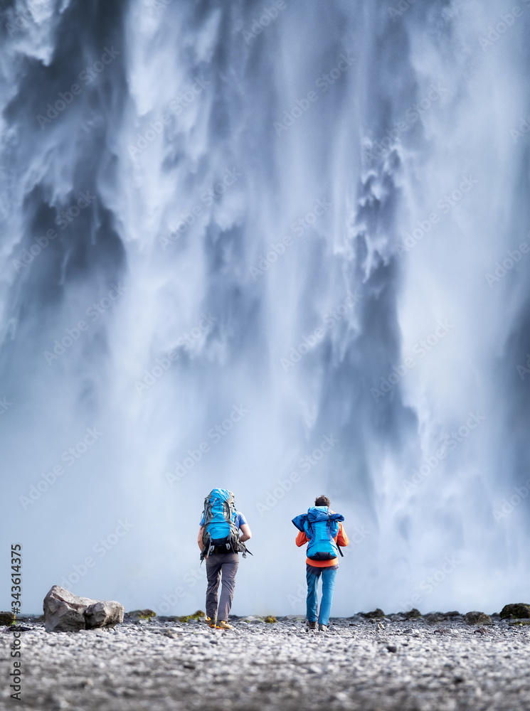 Travelers couple look at the Skogafoss waterfall. Travel and active life concept with team. Adventure and travel in the Iceland. Journey - image