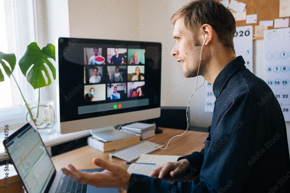 Young man having video call via computer in the home office. Stay at home and work from home concept during Coronavirus pandemic. Virtual house party 