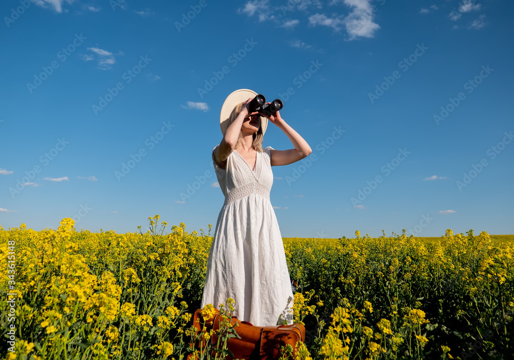 Fototapeta premium woman in dress with suitcase and binoculars in rapeseed field