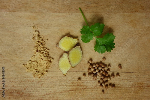 Canvas Print Ginger root and powder and coriander fruits and leaves on wooden trencher