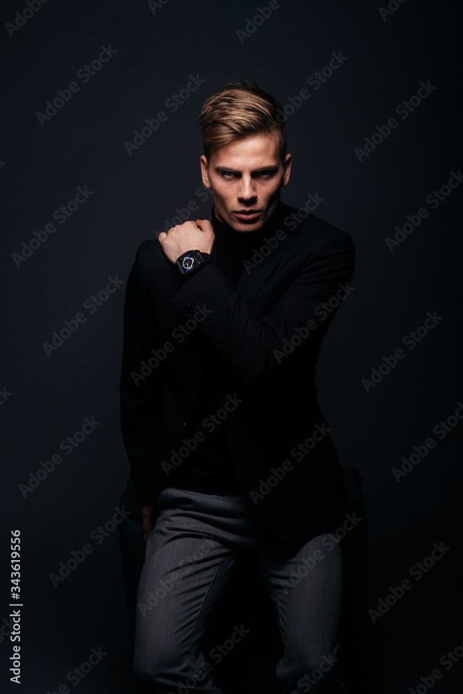 Formally dressed man with sharp jawline in his 20's posing in a studio in front of a black background. Formally dressed man with sharp jawline in his 20's posing in a studio in front of a black background.