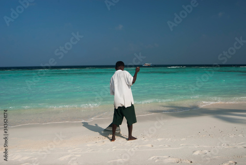 Uomo maldiviano pulisce la spiaggia photo