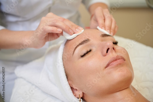 Cleaning forehead with facial sponges in spa treatment professional service