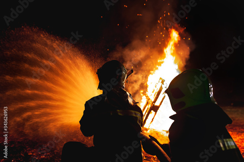 Professional firefighters puttion out a fire with water.