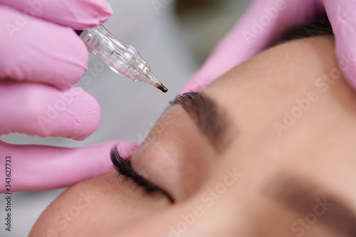 Close up female permanent eyeliner tattoos enhancement coloring in spa photo