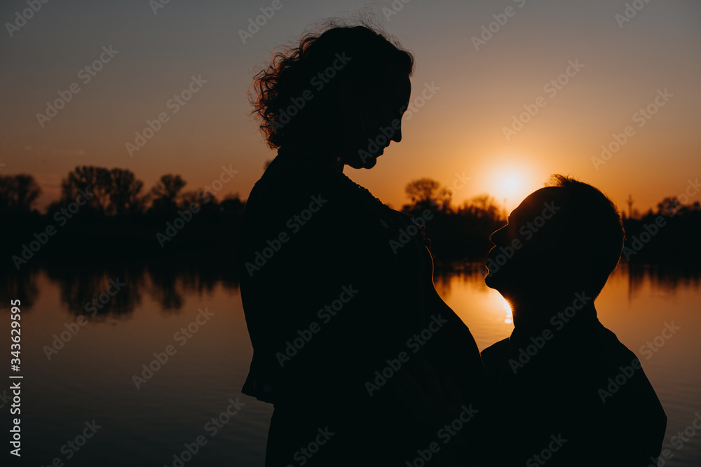 Pretty young pregnant woman with reflection lake in the evening.