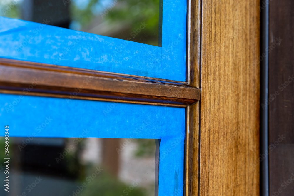Tableau sur toile Wooden door with window, taped off with painter's tape while being refinished