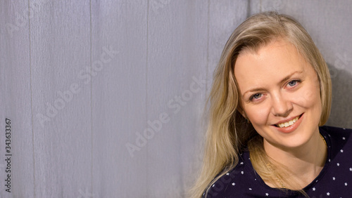 Beautiful smiling blonde girl on a gray background