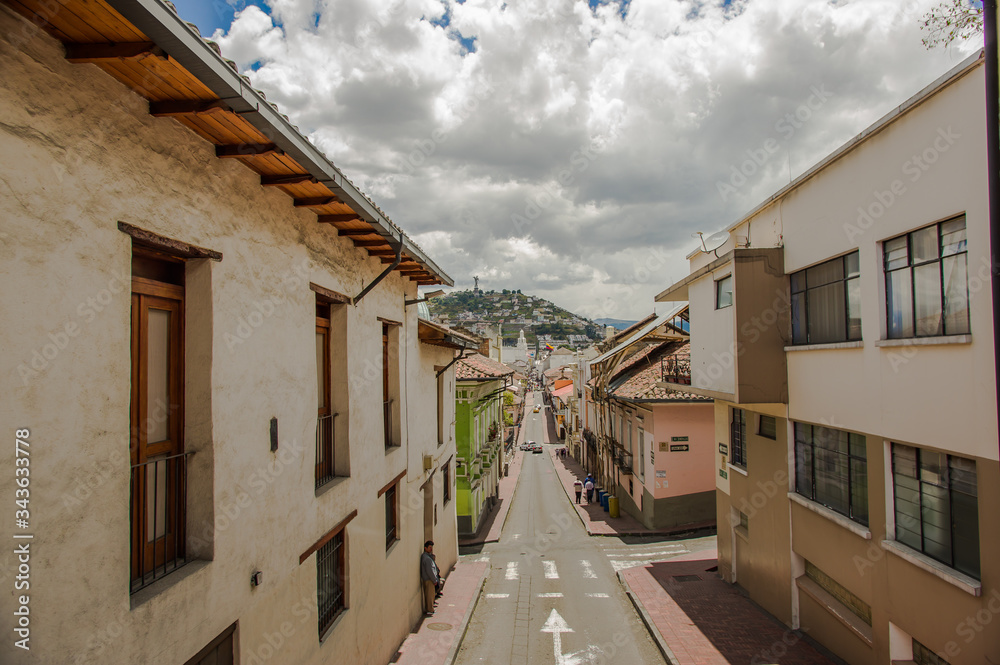 QUITO, ECUADOR - SEPTEMBER 10, 2017: Beautiful view of colonial houses, with the panecito statue in the top of mountain, located in the city of Quito QUITO, ECUADOR - SEPTEMBER 10, 2017: Beautiful view of colonial houses, with the panecito statue in the top of mountain, located in the city of Quito