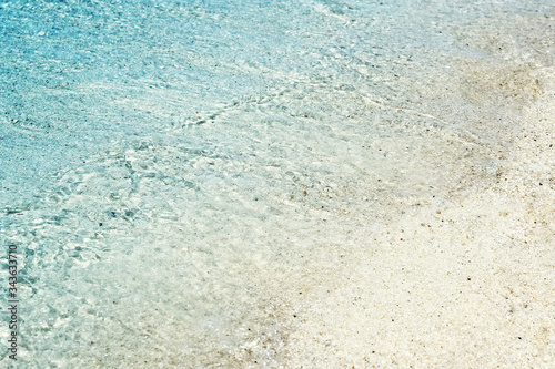 Soft waves with foam of blue ocean on the sandy beach. Background.