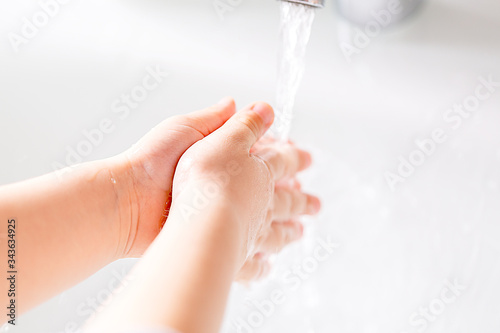 A young child washes his hands under running water.